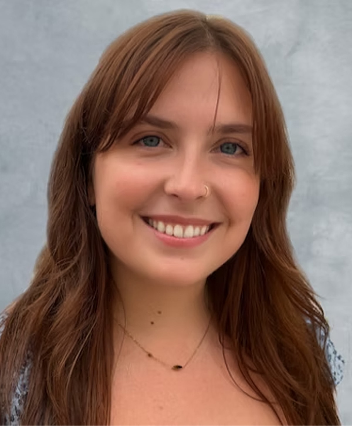 Smiling woman with brown hair and nose ring.
