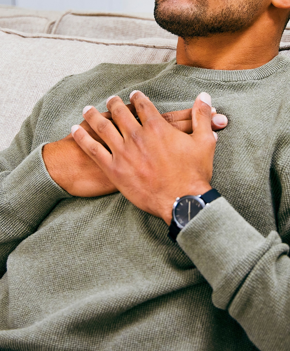 Person relaxing with hands on chest, wearing watch.